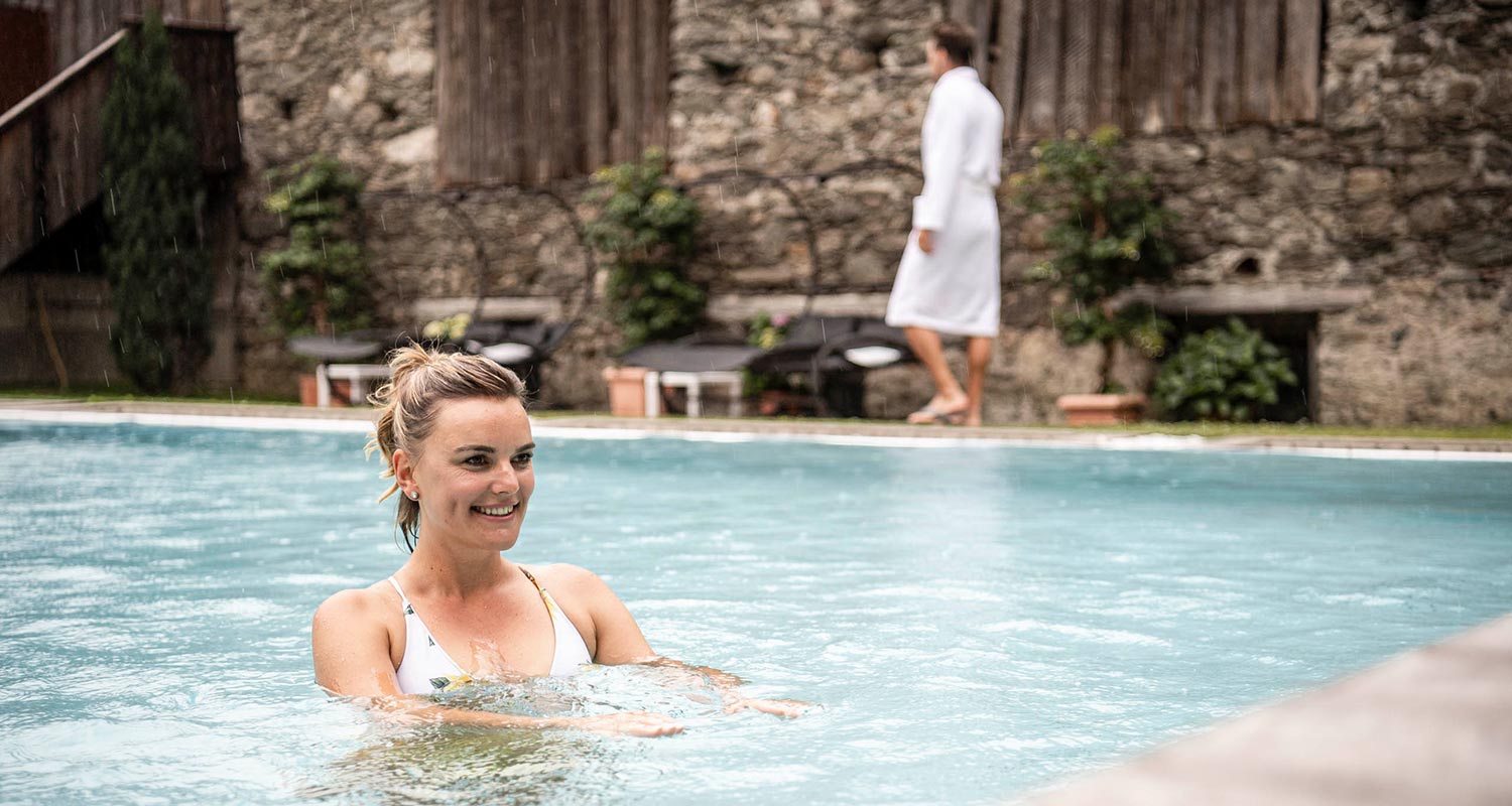 Bildergalerie - SPA - Frau schwimmt im Pool, Mann geht am Pool entlang - Matill